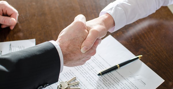 Man shaking hands as he signs a loan
