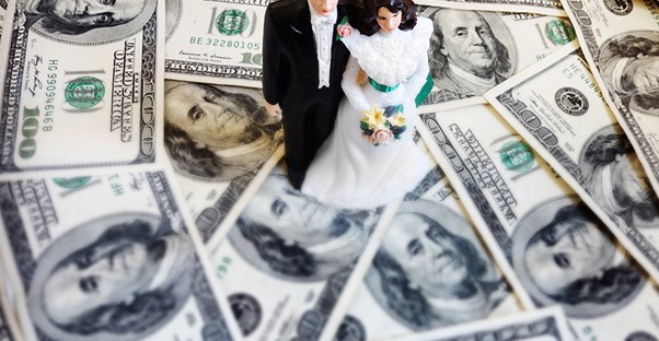 a cake topper couple standing on a pile of money
