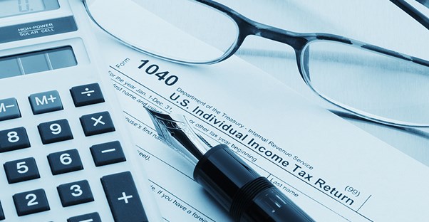 a calculator, a pair of glasses, and a pen laying on top of a 1040 income tax form where you record AGI 