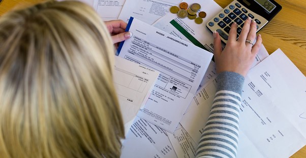 a woman calculating finances on a calculator with multiple bills spread out in front of her