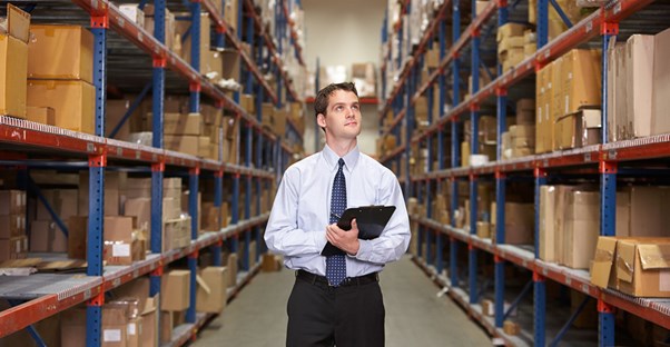 Man standing in a warehouse conducting inventory management.