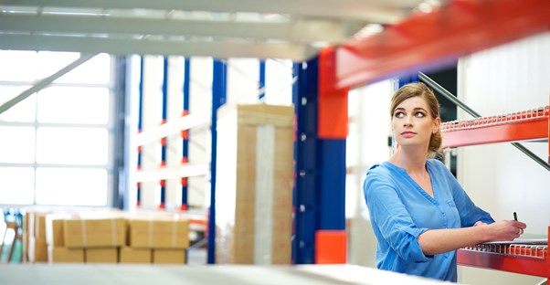Woman conducts inventory management in a large warehouse to save money
