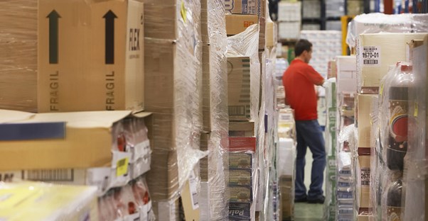 Man checking the information provided in inventory management software against the inventory in the warehouse.