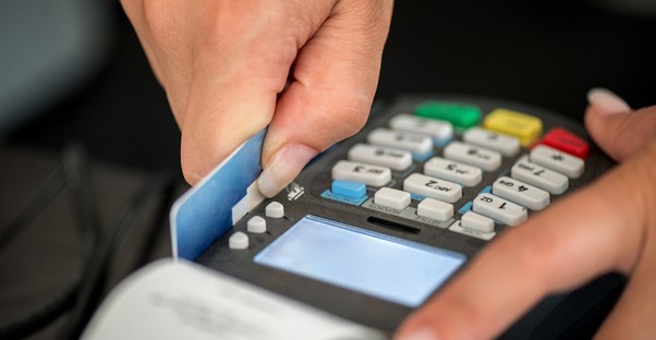 A small business owners swipes a credit card using credit card processing equipment.