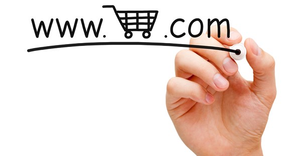 A hand writing a URL with a shopping cart on a glass board to represent marketing an e-commerce business.