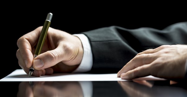 Man in a suit signing for a certificate deposit after reviewing the advantages and disadvantages.