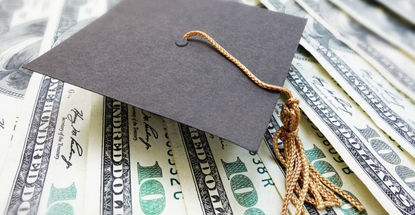 A graduation cap on a stack of money earned through college scholarships.