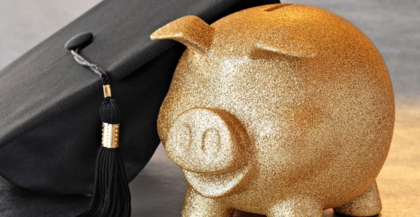 Gold piggy bank next to a graduation cap