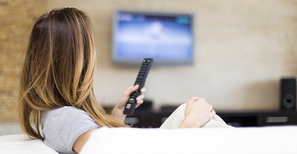 woman watching cable tv on a tv mounted to her wall