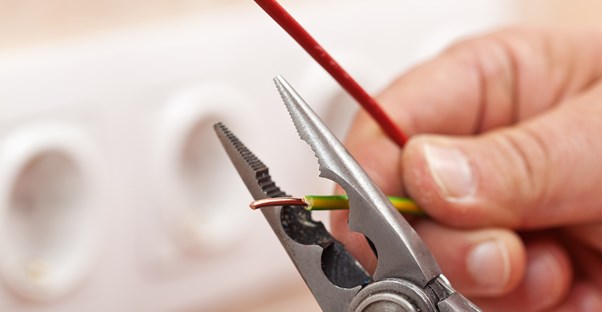 Electrician cuts a wire with a tool