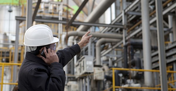A chemical engineer talks on the phone and points to a pipe