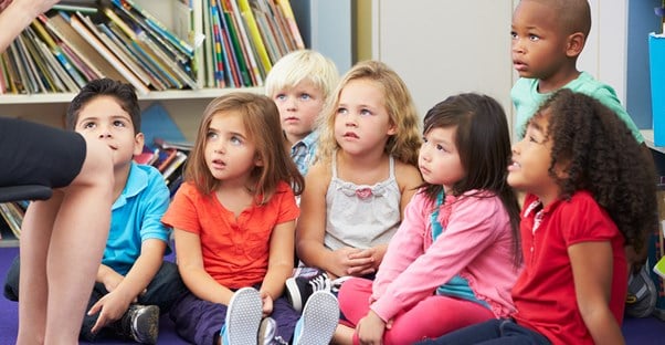 Children listen as their teacher reads them a story