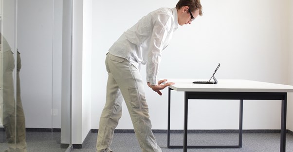 A man stands while working on his computer at the office