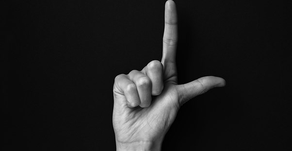 a man using sign language to finger spell the easy letter L to stand for learn