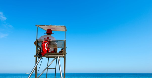 A lifeguard sits in his tower and looks out at the ocean