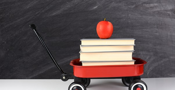 A wagon with books and an apple on top