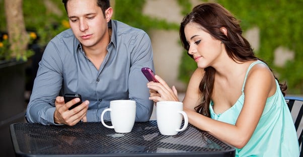 a copule on a date uses their cell phone instead of talking to one another