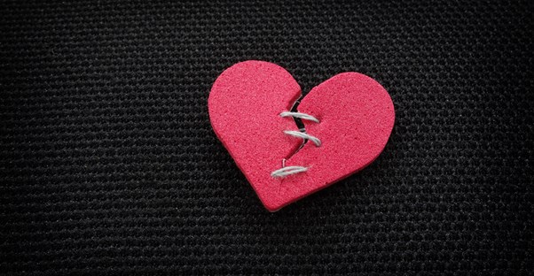A paper heart, broken and stitched together.