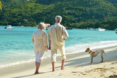 A retired couple walk the beautiful beaches of Tulum, Mexico, with their dog.