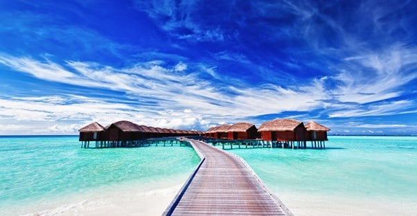 a boardwalk leading to bora bora resort huts located on stilts over the ocean waters