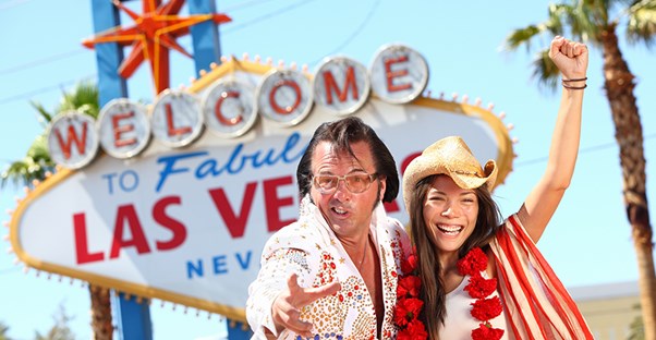 elvis and a woman celebrate their wedding in front of the famous welcome to las vegas sign