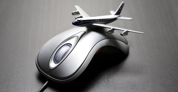 a toy of a commercial airliner perches on top of a computer mouse