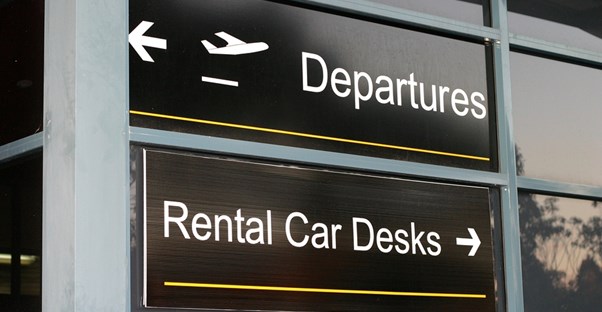 an airport sign pointing the way to the rental car desks