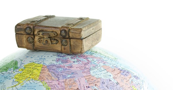 a suitcase, ready to travel, sits on top of a globe