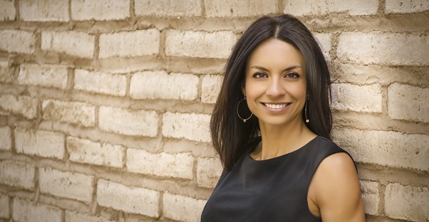 Woman smiles and leans against a wall