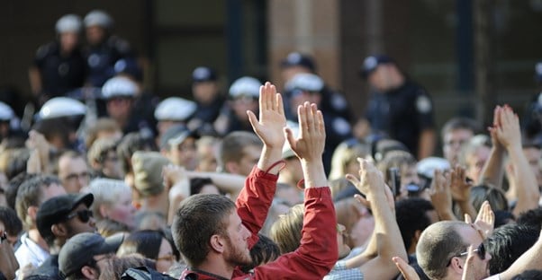 A crowd gets rowdy as police officers look on