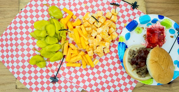 a summer cookout spread with cheese, peppers, bbq, and dessert