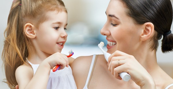 a parent and daughter with different kinds of toothbrushes