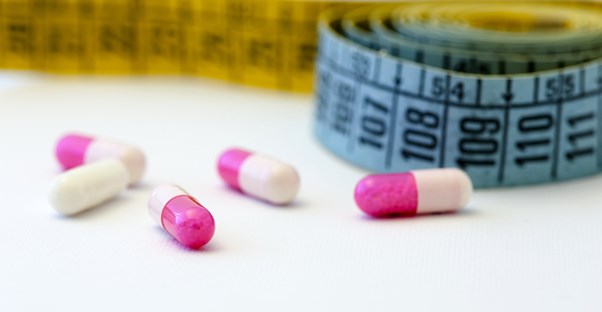prescription diet pills next to a tape measure
