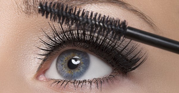 Close up of a woman applying cheap mascara to her eyelashes.