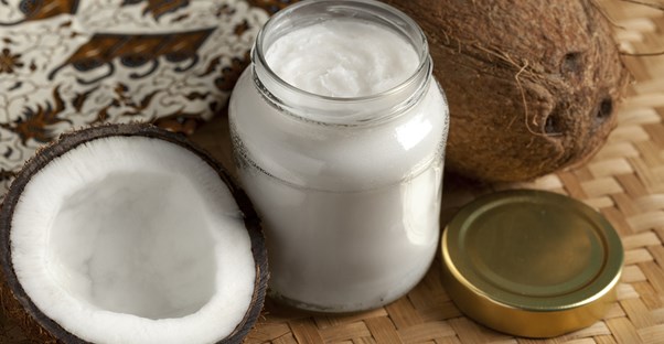 a full jar of coconut oil surrounded by real coconuts