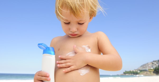 a child rubs sunscreen on his stomace
