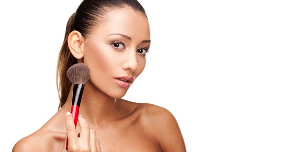 a woman contours her makeup around her cheekbones