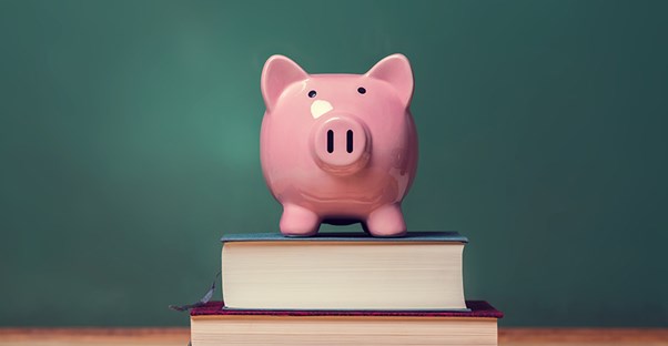 piggy bank sitting on top of textbooks