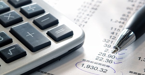 A business' financial sheet with a calculator and a pen