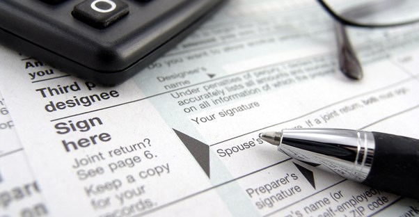 Close up of tax form 990 with a calculator and pen