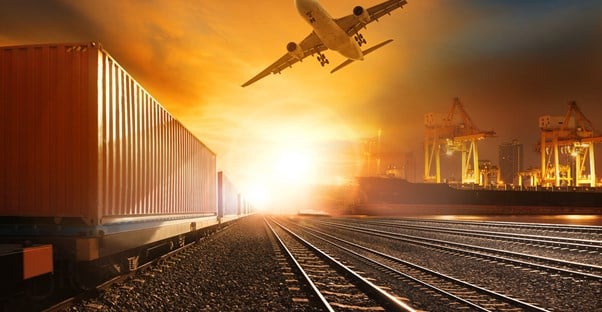 Sunset with plane, train tracks, and a shipping container in the foreground
