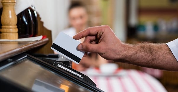 Man arm swiping a credit card at a point of sale terminal