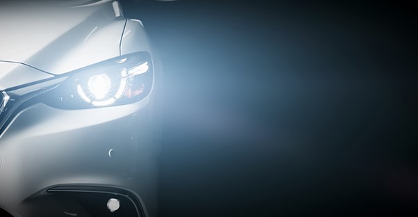 the headlight of a luxury car shines toward the camera