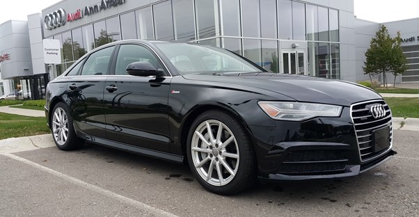 a black 2018 audi a6 in front of a dealership