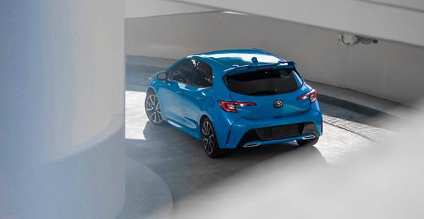 a blue 2019 toyota corolla hatchback drives down a parking garage ramp