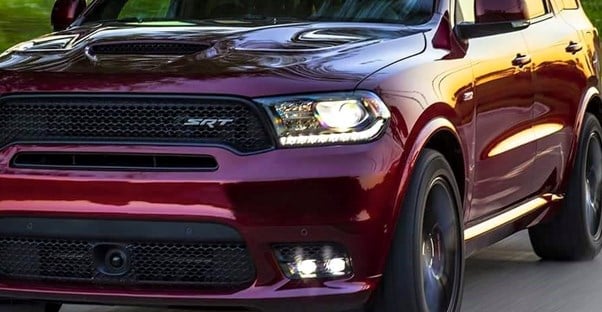 the front of a maroon dodge durango as it drives along a road