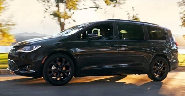 a 2019 chrysler pacifica minivan driving with the sunset behind it