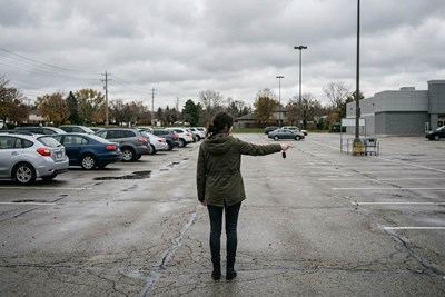 A woman trying to unlock a car in the parking lot with the fob