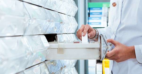 Pharmacy technician filing away medications