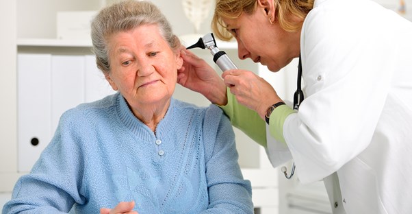 An audiologist checks an elderly woman's ears
